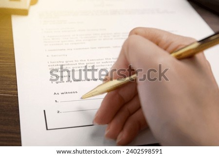 Woman signing Last Will and Testament at table, closeup