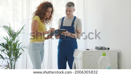 Woman signing the plumber invoice, he repaired her washing machine