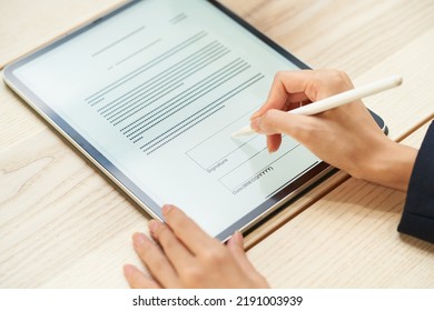 A woman signing using a tablet PC and stylus pen - Shutterstock ID 2191003939