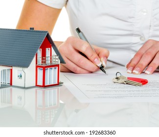 a woman signs a contract to purchase a home with a real estate agent.