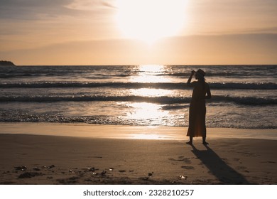 woman silhouette against calm sunset beach - Powered by Shutterstock