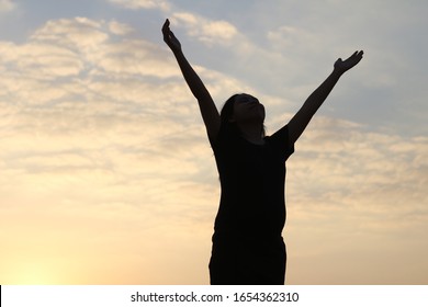 Woman Silhouette Arms Up To The Sunset Feeling Happy And Freedom.