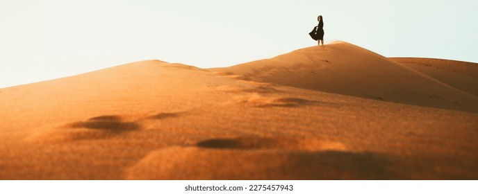 Woman silhouette enjoy sand dunes in desert in sunset blue hour alone. Travel lifestyle and wellness concept. Cinematic wanderlust background - Powered by Shutterstock