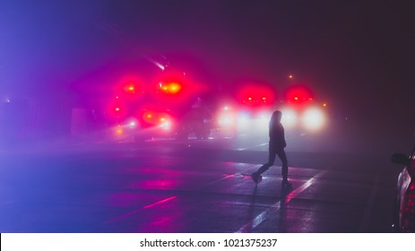 A Woman Silhouetted Against The Lights Of Emergency Vehicles