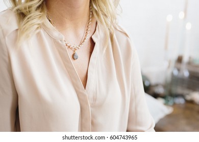 A Woman In A Silk Shirt Wearing A Pendant Necklace