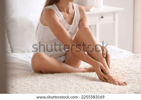 Woman with silky legs sitting on bed at home