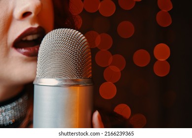 Woman singer with disco mic on bokeh light background. Close-up of female's lips painted with burgundy lipstick and retro microphone. Redhead girl starting concert. Copy space for gig posters. - Powered by Shutterstock