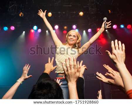 Woman singing in concert on stage in front of adoring fans low angle view