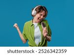 Woman singing, dancing with hair brush instead microphone on Blue background. Lady having fun, listening to music, karaoke, dreams of being celebrity. High quality