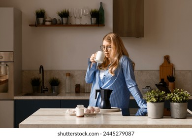 Woman sipping coffee in sunlight kitchen. Morning routine - Powered by Shutterstock