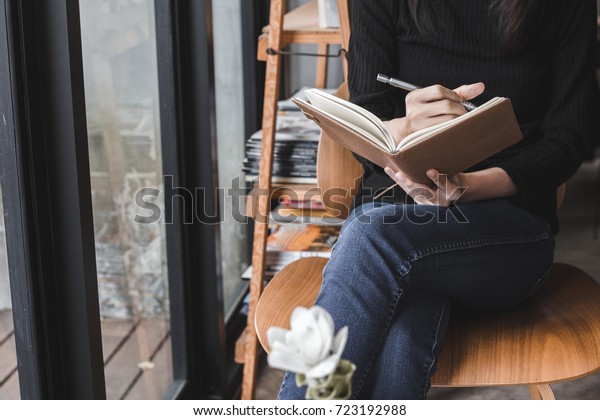 woman sit\
down to writting a notebook on her\
legs