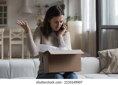 Woman sit on sofa open parcel box looks inside check purchased damaged items feels angry, complaining speaks on smartphone to customer support. Broken goods, bad services, dissatisfied client concept