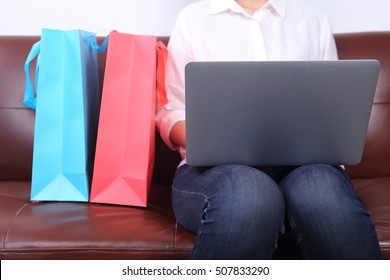 Woman sit on sofa with shooping bag beside and using laptop - Shutterstock ID 507833290