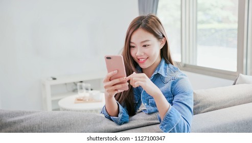 Woman Sit On Sofa And Use Phone Happily At Home