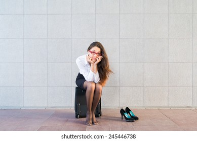 Woman sit on suitcase without shoes