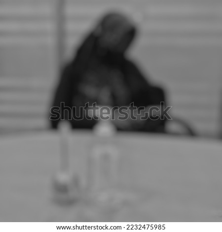 a woman sitdown and playing her cellphone behind a pen and hand sanitizer, Bogor, INDONESIA 