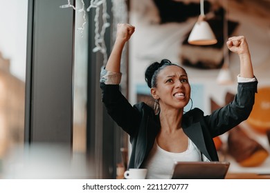 A Woman Sits In A Cafe With Her Arms Raised And Celebrating A Job Well Done.Business Concept