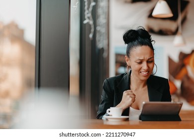 A Woman Sits In A Cafe With Her Arms Raised And Celebrating A Job Well Done.Business Concept