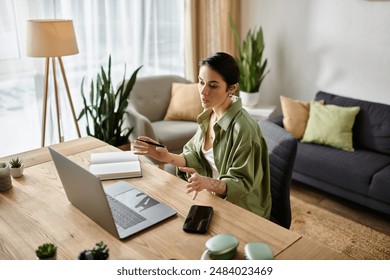 A woman sits at her desk in a home office, focused on her work. - Powered by Shutterstock