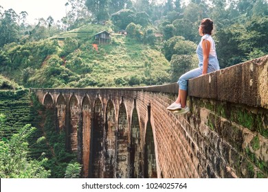 Woman sits on the Demodara nine arches bridge the most visited sight of Ella town in Sri Lanka