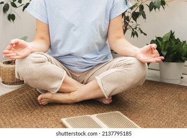 Woman sits on the floor in Yoga posture, a wooden sadhu board with nails, for sadhu practice at home