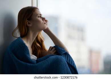 woman sits on the windowsill and looks out the window                       