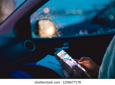 A woman sits in the passenger seat of a car and uses a smartphone in the early winter morning - Shutterstock ID 1258677178