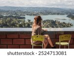 A woman sits at a restaurant overlooking a Lake