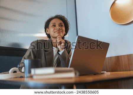 A woman sits at a table with a laptop, a whitecollar worker at an event