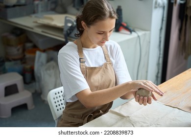 Woman Sits At Table And Works With Lump Of Clay