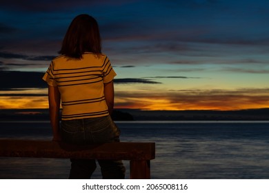 A Woman Sitting Alone By The Sea At Sunset, She Looked So Sad And Hopeless. Heartbroken And Fail About Love