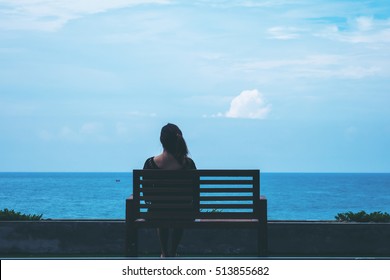 A woman sitting alone on a chair in front of the sea with feeling lonely