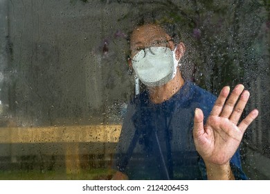 Woman Sitting Alone, Wearing Mask From Behind Wet Window Glass After The Rain