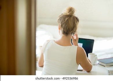 Woman Sitting Back Talking On The Phone At Table With A Cup And Laptop On It. Rear View. Concept Photo