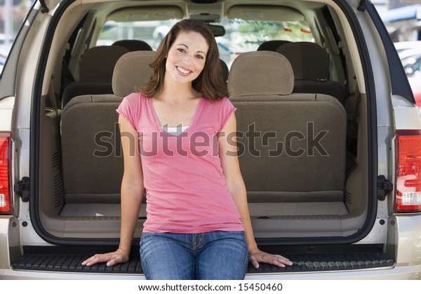 Woman sitting in back of\
van smiling