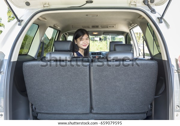 Woman sitting in back of\
van smiling