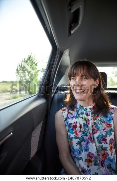 woman sitting in the backseat of a car while\
looking through the closed\
window