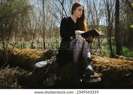 Woman sitting in a black robe with a skull and book in the dark forest swamp. Mystical portrait of a witch. The concept of witchcraft and occultism.