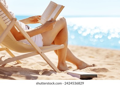 Woman sitting with book in the chaise lounge on the sea beach. - Powered by Shutterstock