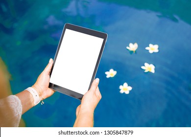 Woman sitting by the pool and using tablet computer. Vertical white screen .