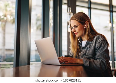 Woman sitting at cafe table and working on laptop computer. Female surfing internet on laptop using cafe wifi.