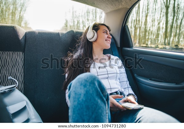 woman sitting at car backseats and listening\
music. car travel concept