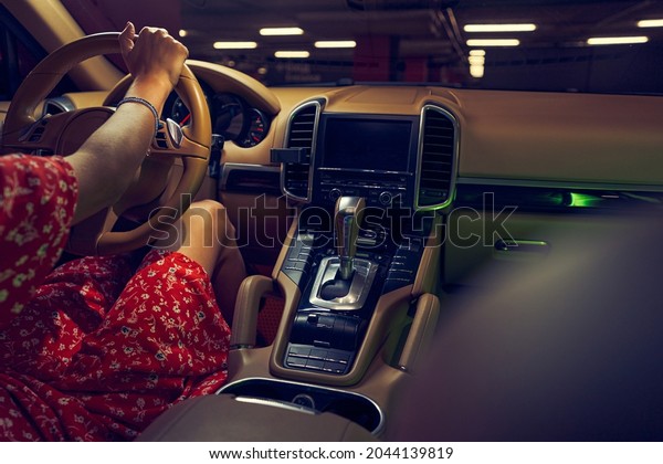 Woman\
sitting in car with control panel and gear\
shift