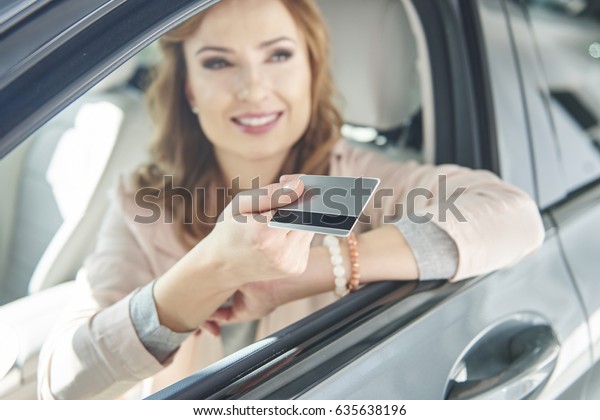 Woman sitting in a car\
with credit card 