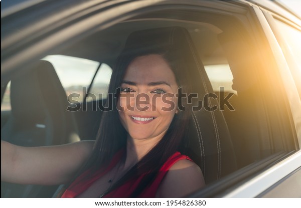 woman sitting in a car driving\
with the sun shining - automotive industry concept - selective\
focus