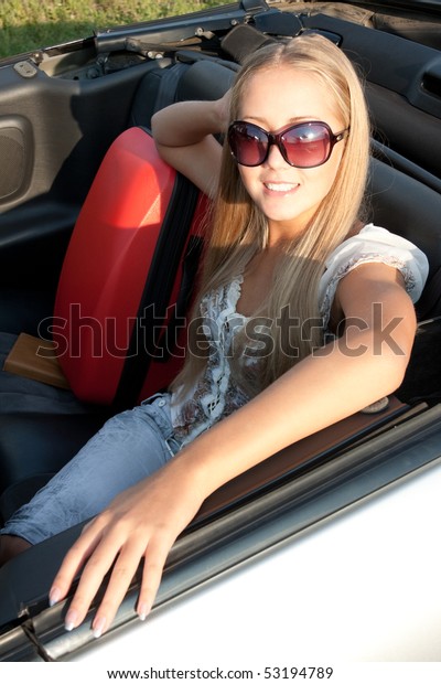 Woman sitting in a\
car, with her baggage