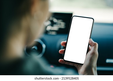 Woman sitting in car and holding blank white phone. Mockup empty background - Shutterstock ID 2139528405