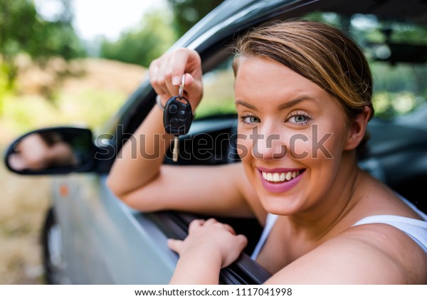 Woman Sitting In Car With Key. Happy woman with\
key. Woman buying car. Woman Driver Holding Keys siting in Her New\
Car. Driving towards the fun. Auto business, car sale, consumerism\
and people concept