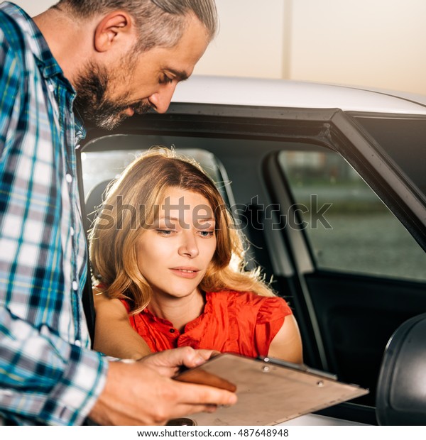 Woman\
sitting in the car and reading car rental\
agreement