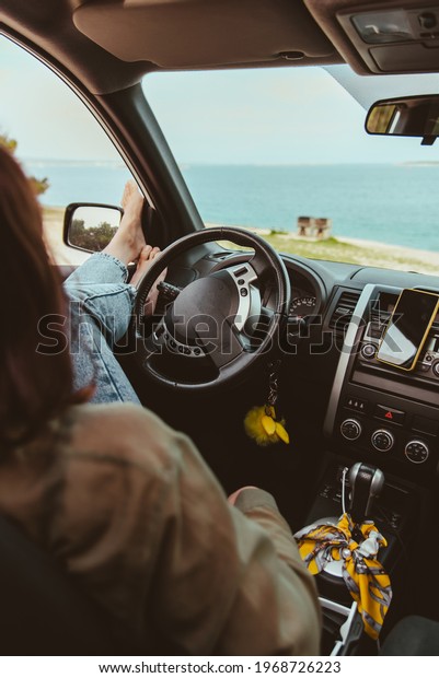 woman sitting in car relaxed and looking at sea\
beach. summer vacation